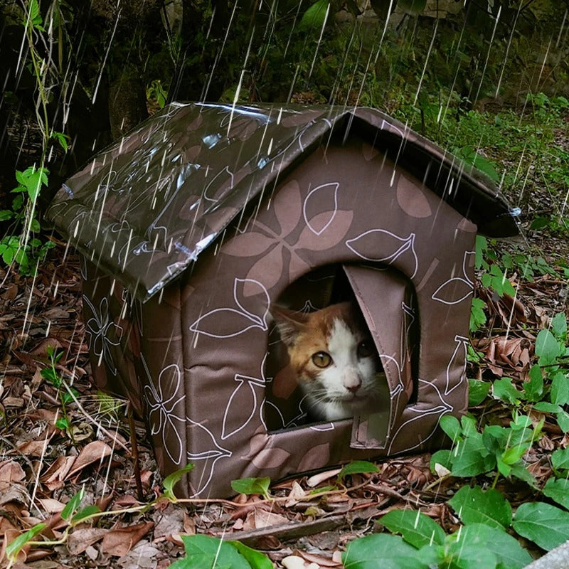Niche pour chat extérieur brune à motifs feuille avec chat roux à l'intérieur, résistante à la pluie en forêt.