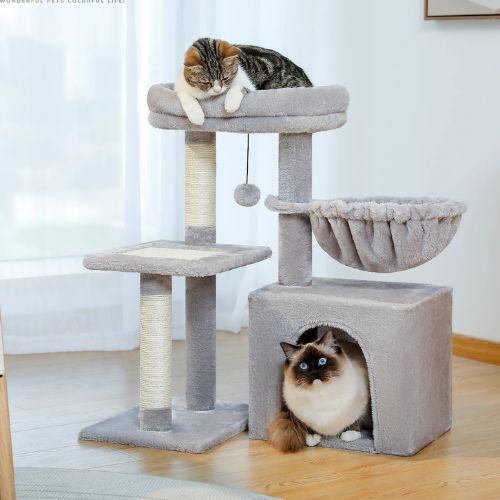 Arbre a chat gris avec grande niche carrée, hamac et plateau supérieur rembourré, deux chats installés pour se reposer sur les différents niveaux dans le salon.