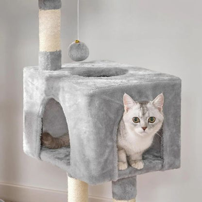  Chat gris argent installé dans la niche d’un arbre a chat gris, pompon suspendu au-dessus et poteaux en sisal servant de griffoirs robustes.