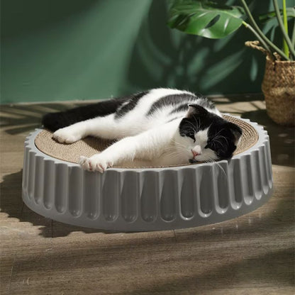 Un chat allongé sur un griffoir rond en carton
