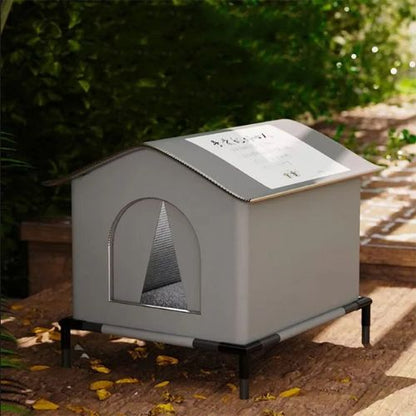 Niche pour chat extérieur grise sur plateforme surélevée installée sur une terrasse en bois avec feuilles d'automne
