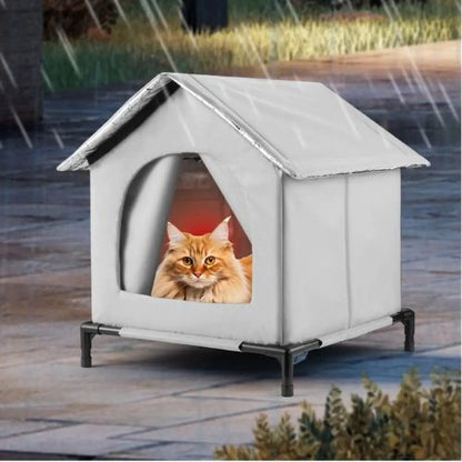 Niche pour chat extérieur grise avec toit incliné, chat à l'intérieur regardant par la porte arquée, montée sur plateforme surélevée