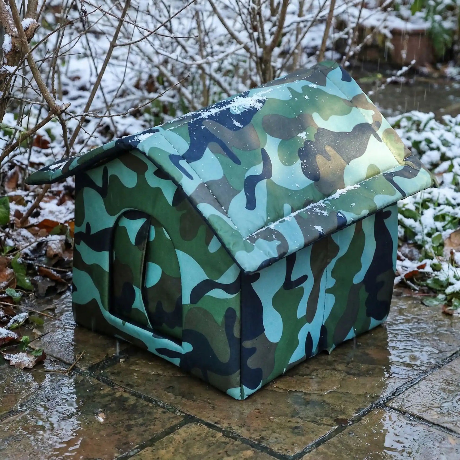 Une niche pour chat extérieur placée dans un jardin dans un temps pluvieux. la nporte coupe vent